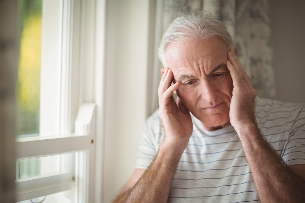 Stressed senior man standing by window